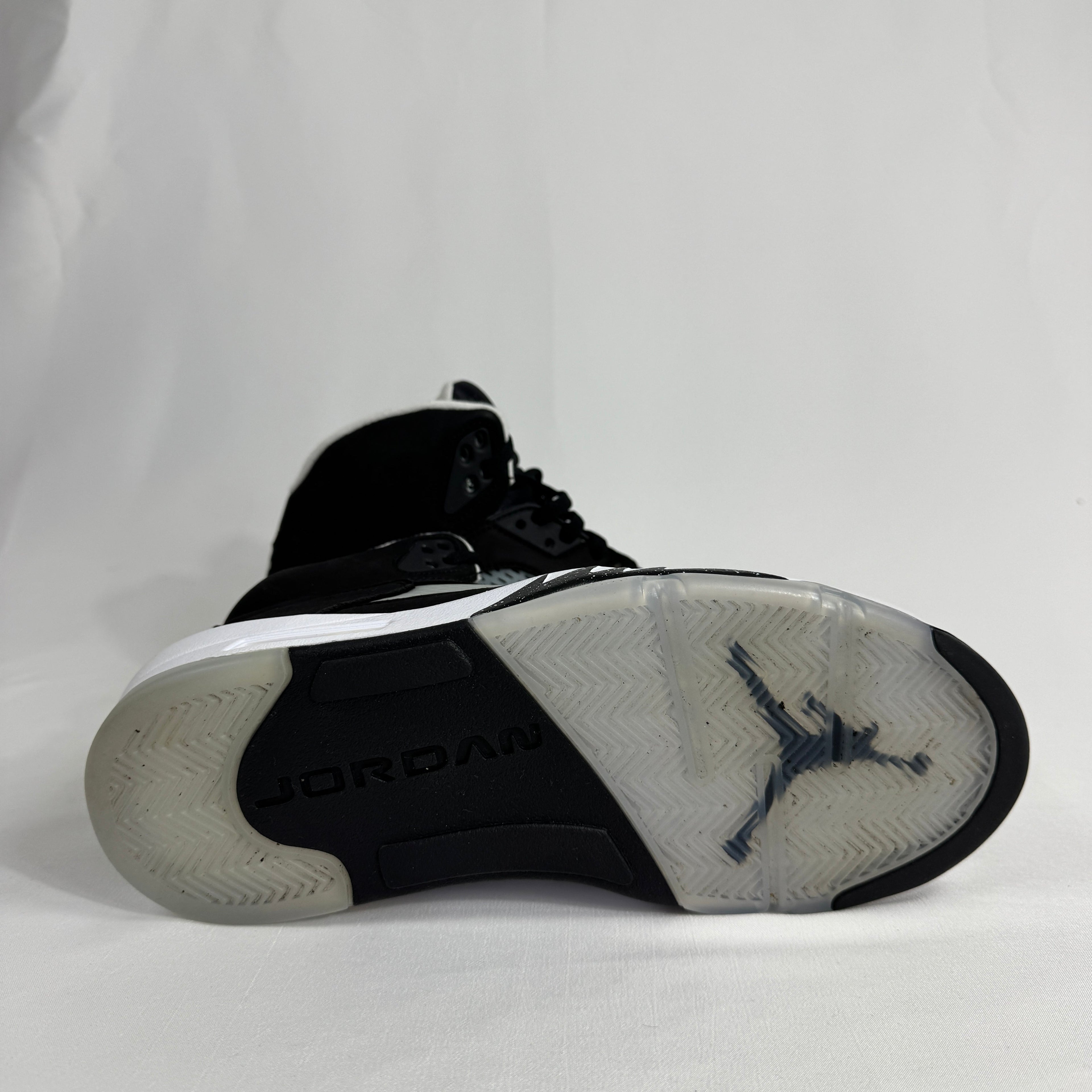 The Jordan 5 Retro Oreo is a classic basketball-inspired sneaker featuring a black nubuck upper, signature reflective