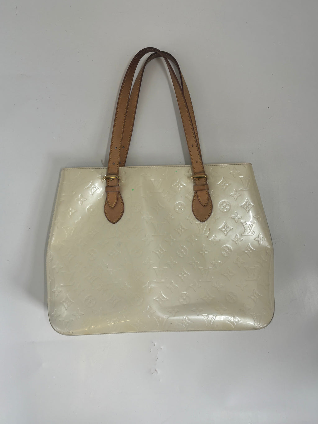 Louis Vuitton butter yellow handbag with embossed pattern and two brown leather shoulder straps on a white background.