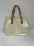 Louis Vuitton butter yellow handbag with embossed pattern and two brown leather shoulder straps on a white background.