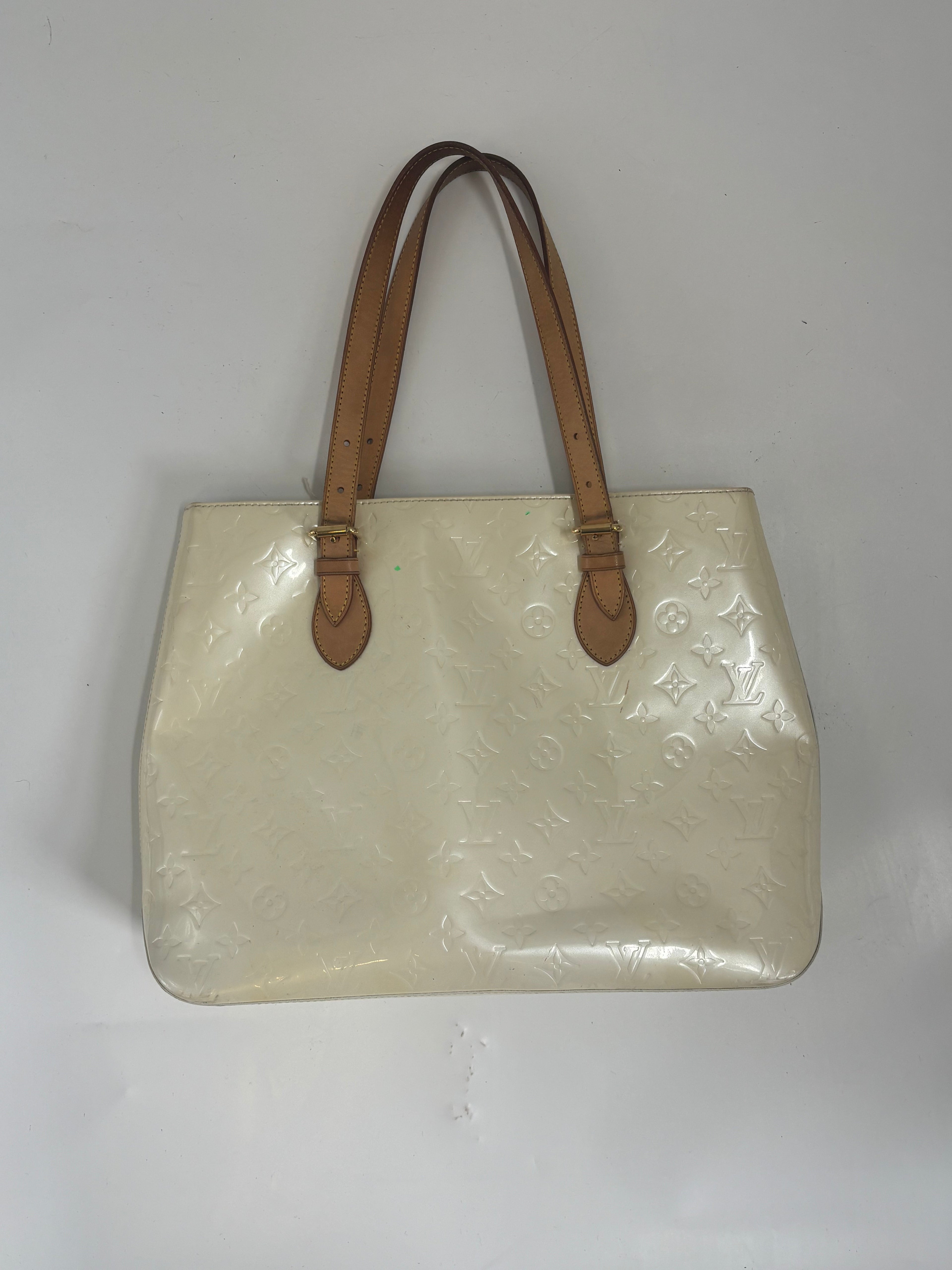 Louis Vuitton butter yellow handbag with embossed pattern and two brown leather shoulder straps on a white background.