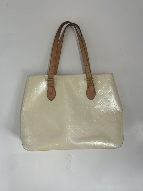 Louis Vuitton butter yellow handbag with embossed pattern and two brown leather shoulder straps on a white background.