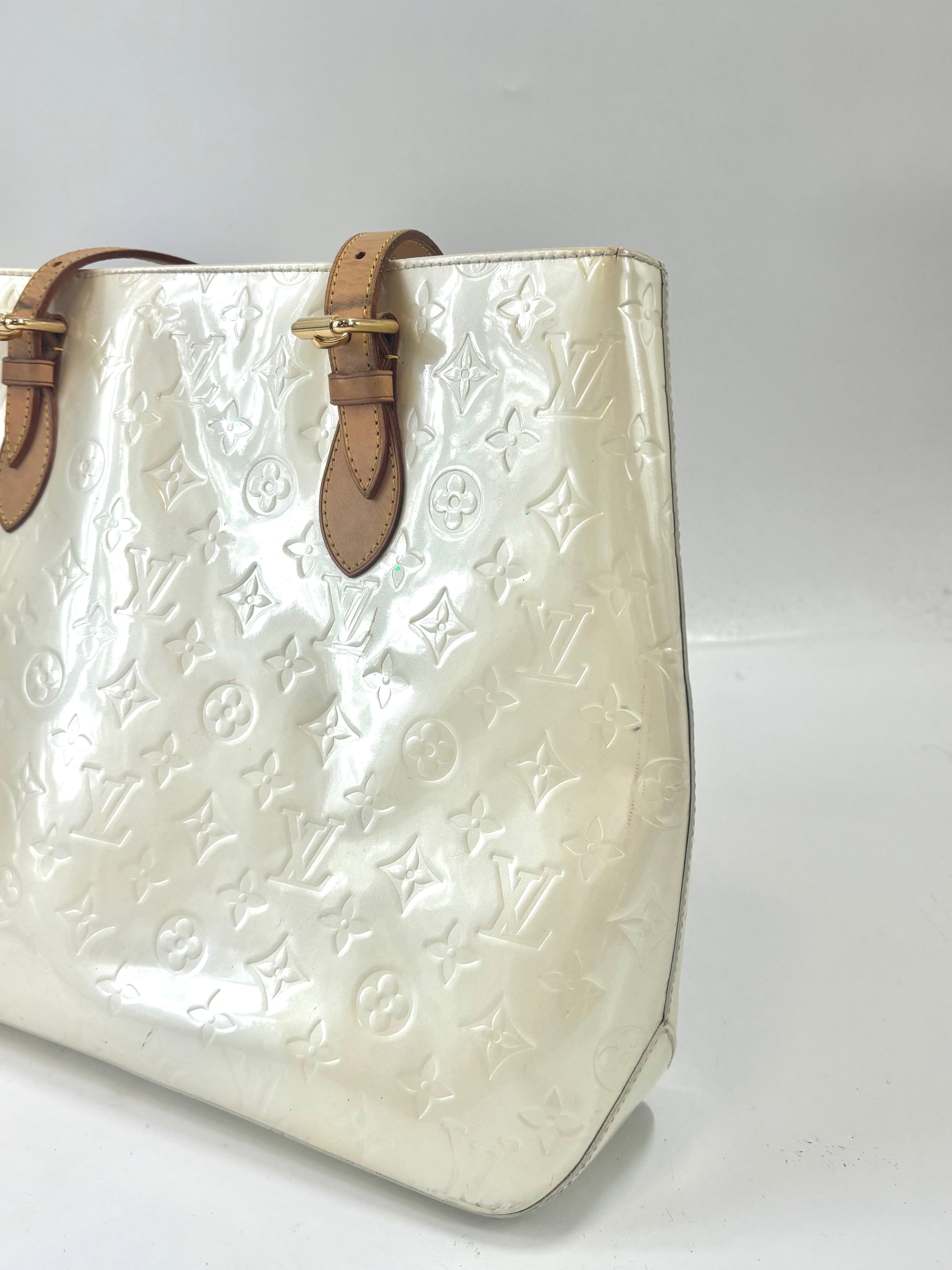 Close-up of a Louis Vuitton yellow handbag with embossed monogram, brown leather straps and gold buckles on a white background.