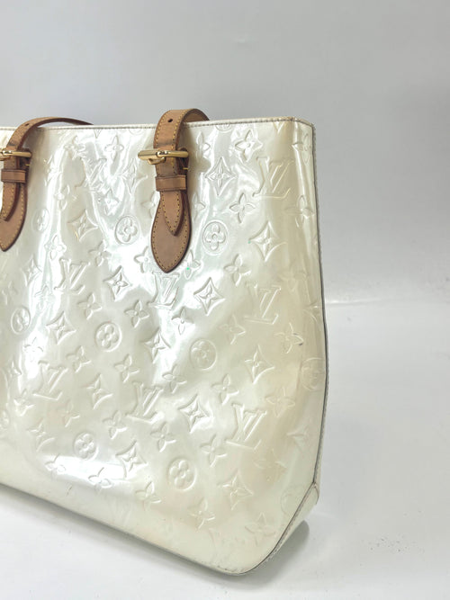 Close-up of a Louis Vuitton yellow handbag with embossed monogram, brown leather straps and gold buckles on a white background.