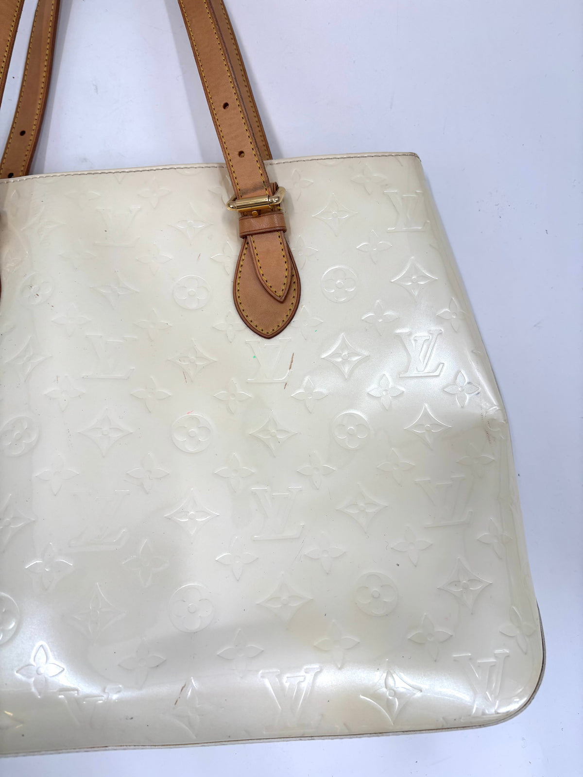 Close-up of a Louis Vuitton Butter Yellow handbag with light brown leather handles and embossed monogram pattern.