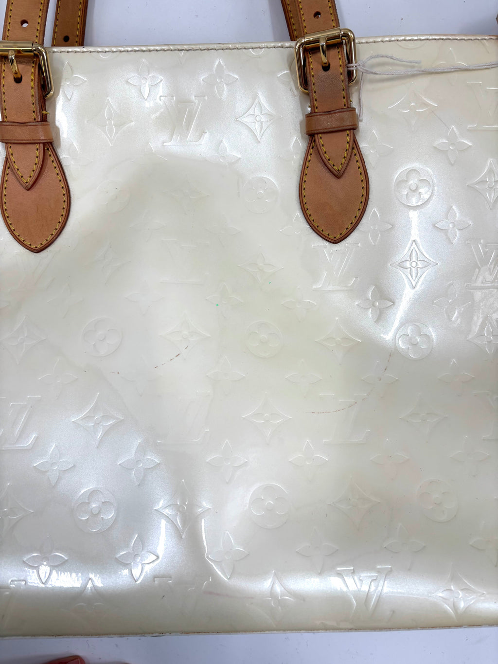 Close-up of a butter yellow Louis Vuitton handbag in patent leather with tan handles and embossed monogram detailing.