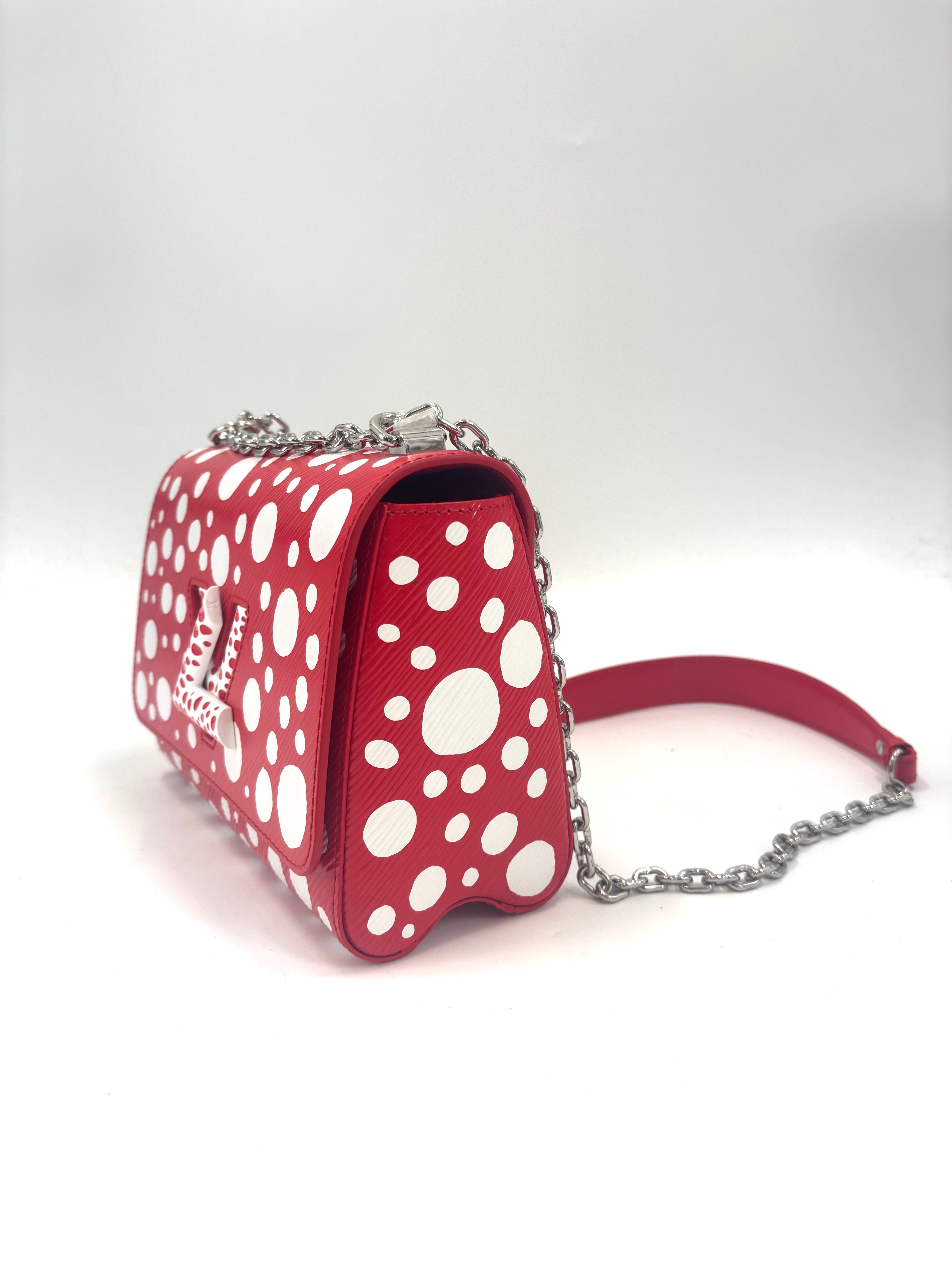 Red Louis Vuitton Twist bag with white polka dots, silver chain strap and textured clasp shown on a plain white background.