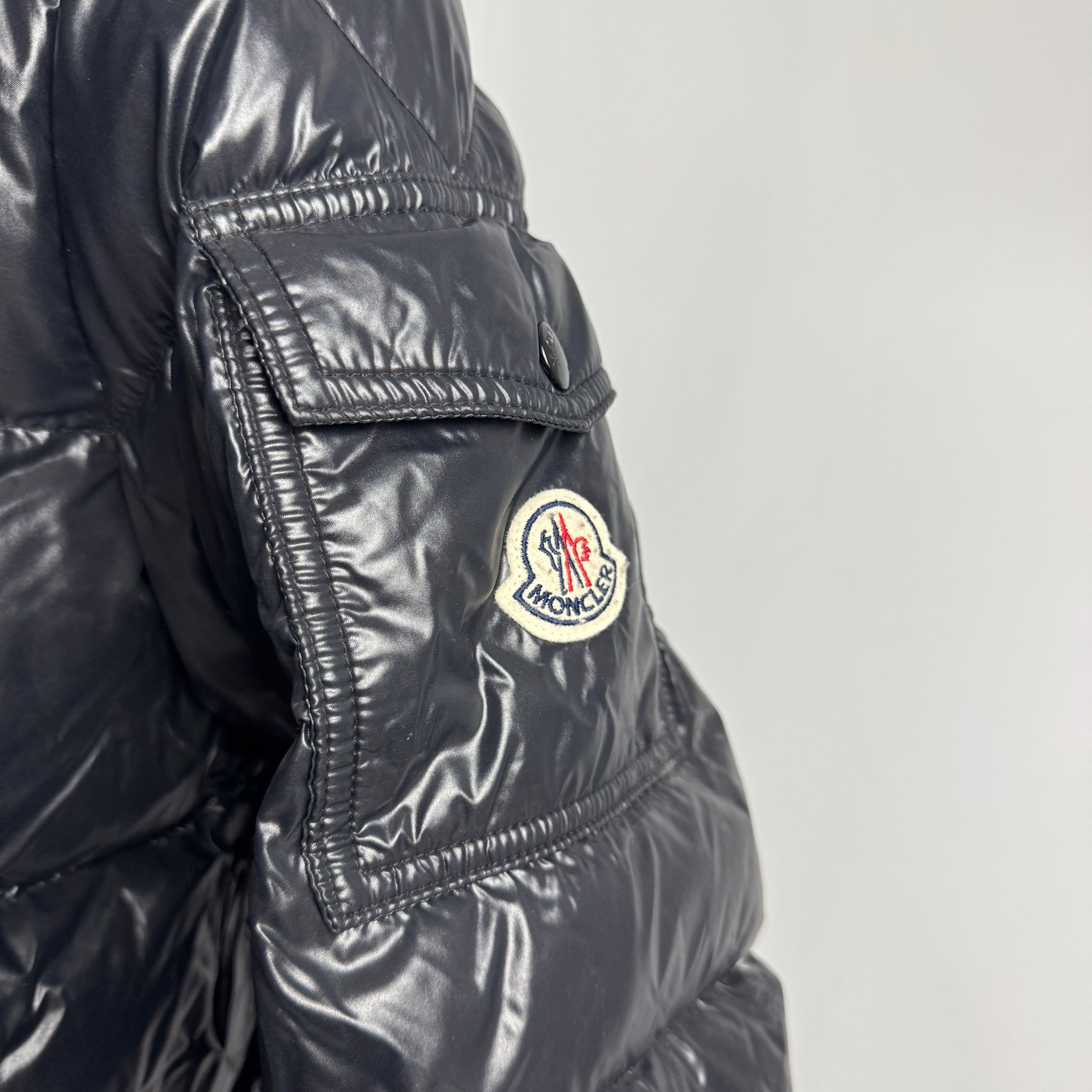 The Moncler Maya jacket is a short, glossy down puffer known for its boxy fit, strong insulation, detachable hood, and