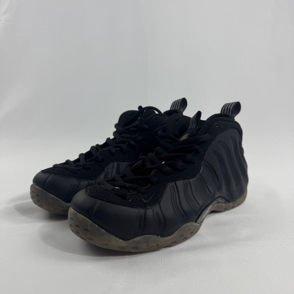 Black Nike trainers with textured sides, thick rubber soles and black laces, displayed against a plain white background.