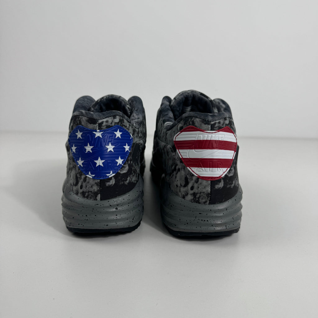 Black and grey Nike Air Max Lunar90 SP trainers seen from behind, featuring hearts with American flag motifs on each heel.