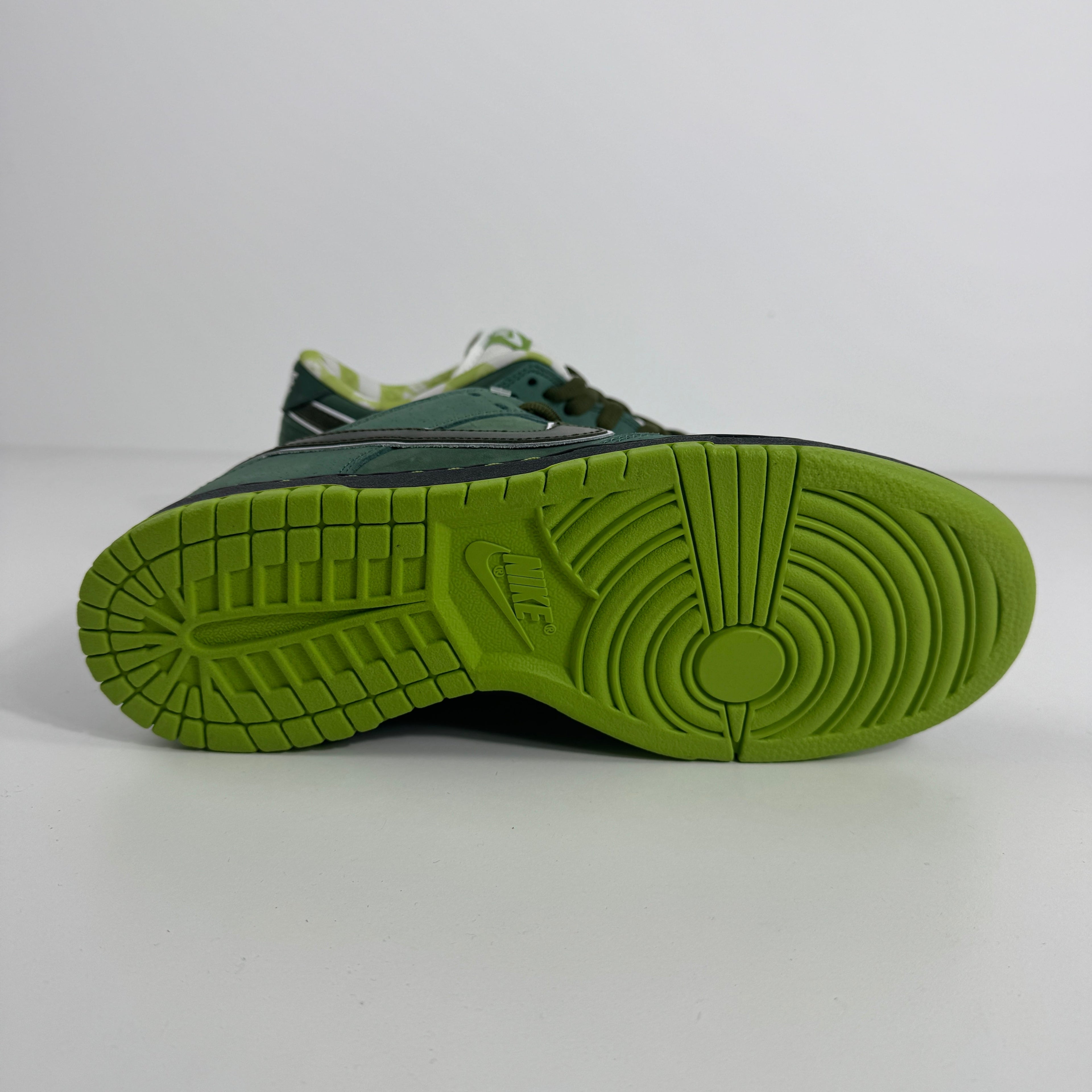 Nike SB Dunk Low trainer shown side-on with a green sole, Nike logo and textured grip pattern on a plain white background.