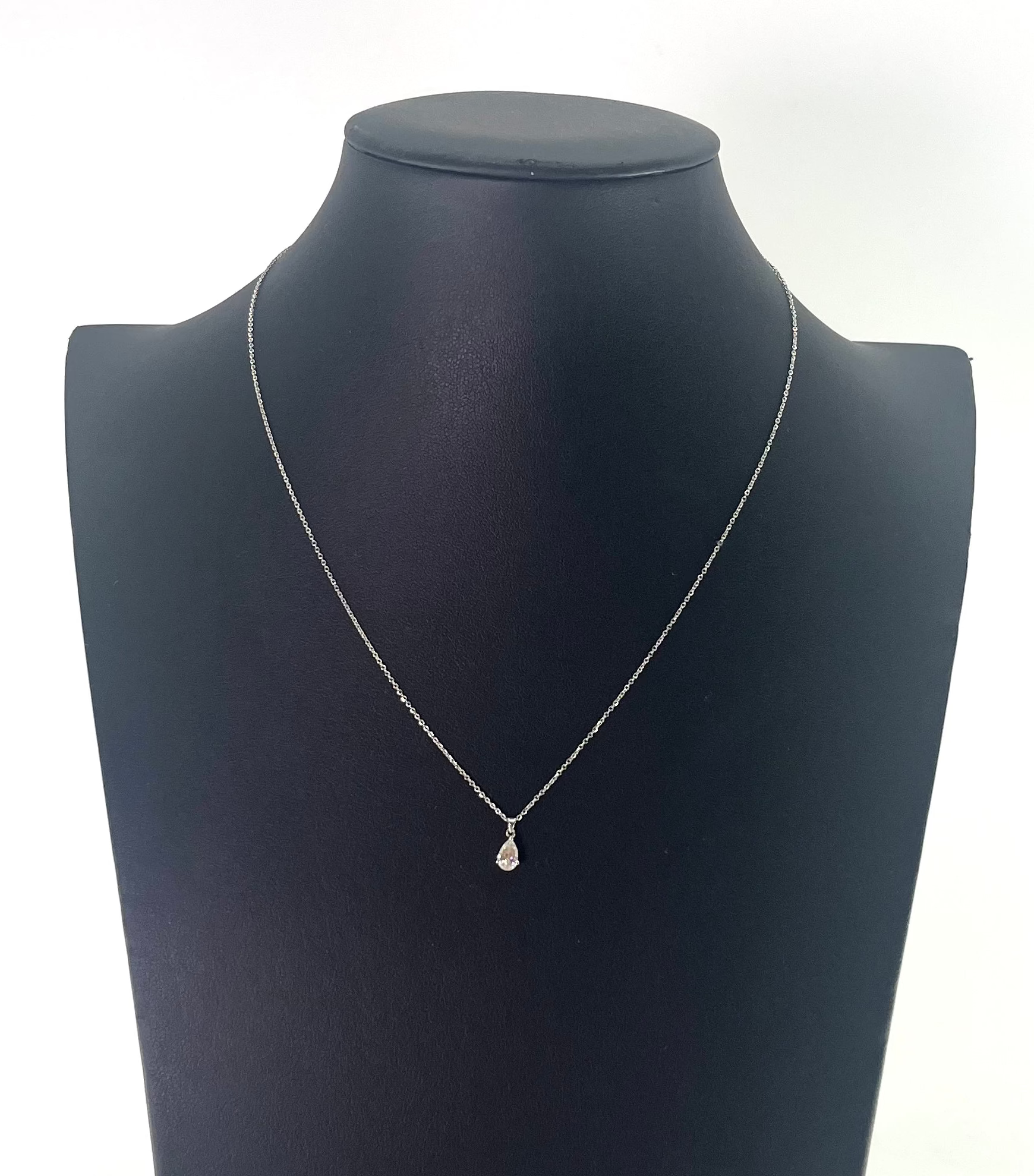 CB STORES pear-shaped diamond pendant necklace on a platinum chain, shown on a black jewellery bust with a white background.