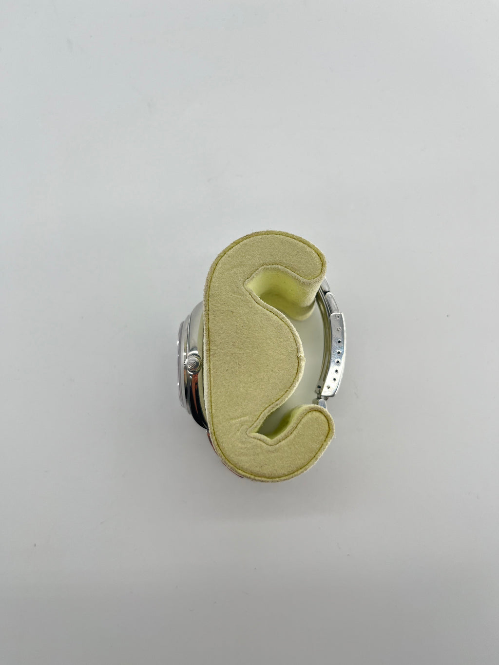 A Rolex Air-King watch with a stainless steel case is shown from above on a light yellow foam holder against a white background.