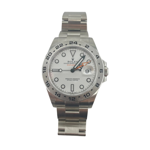 Rolex Explorer II silver wristwatch with a white dial, black markers and hands, orange GMT hand, date window, and metal link bracelet.