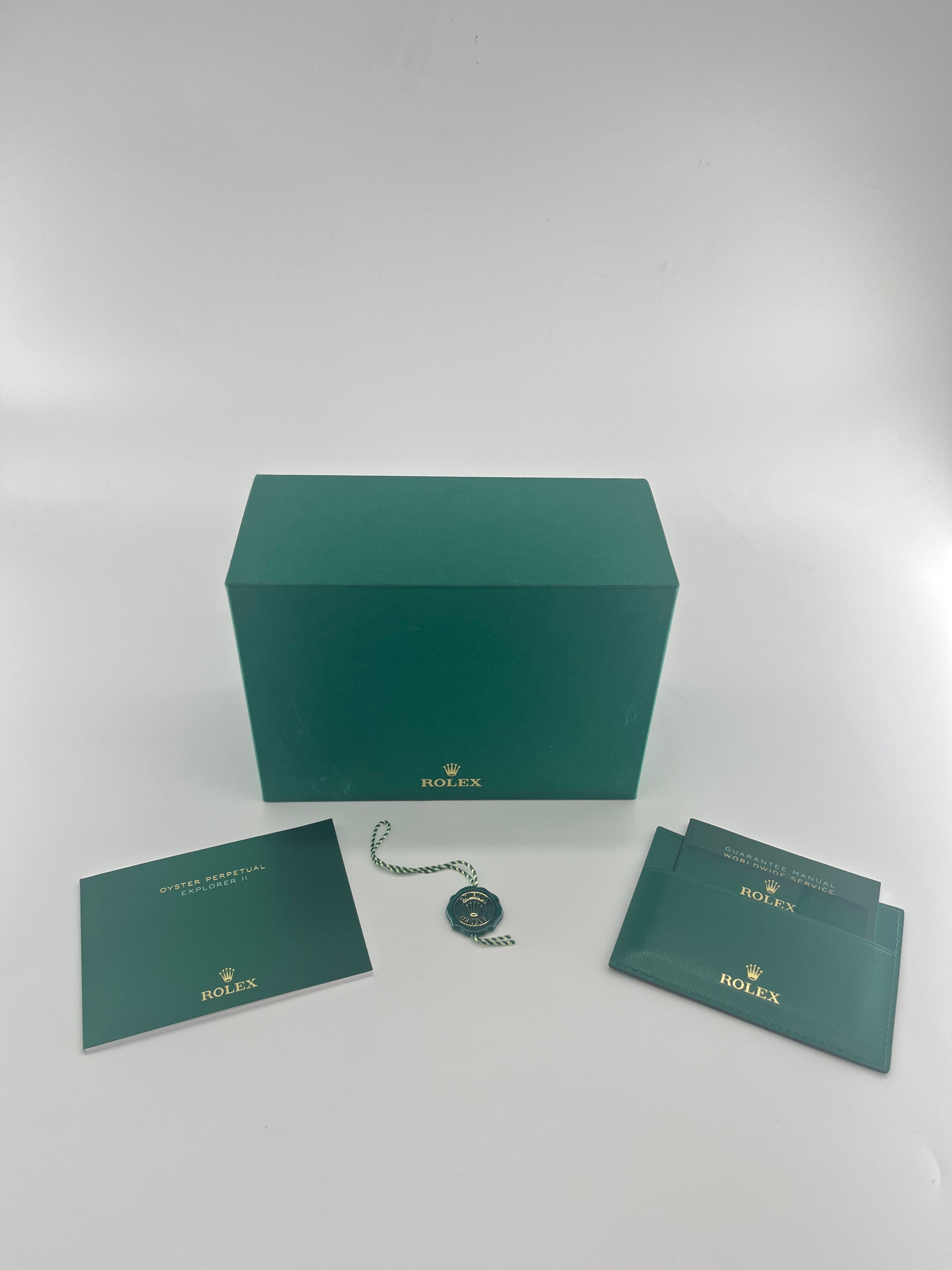 Green ROLEX box with two booklets, an instruction manual, and a green and gold ROLEX tag displayed in front.