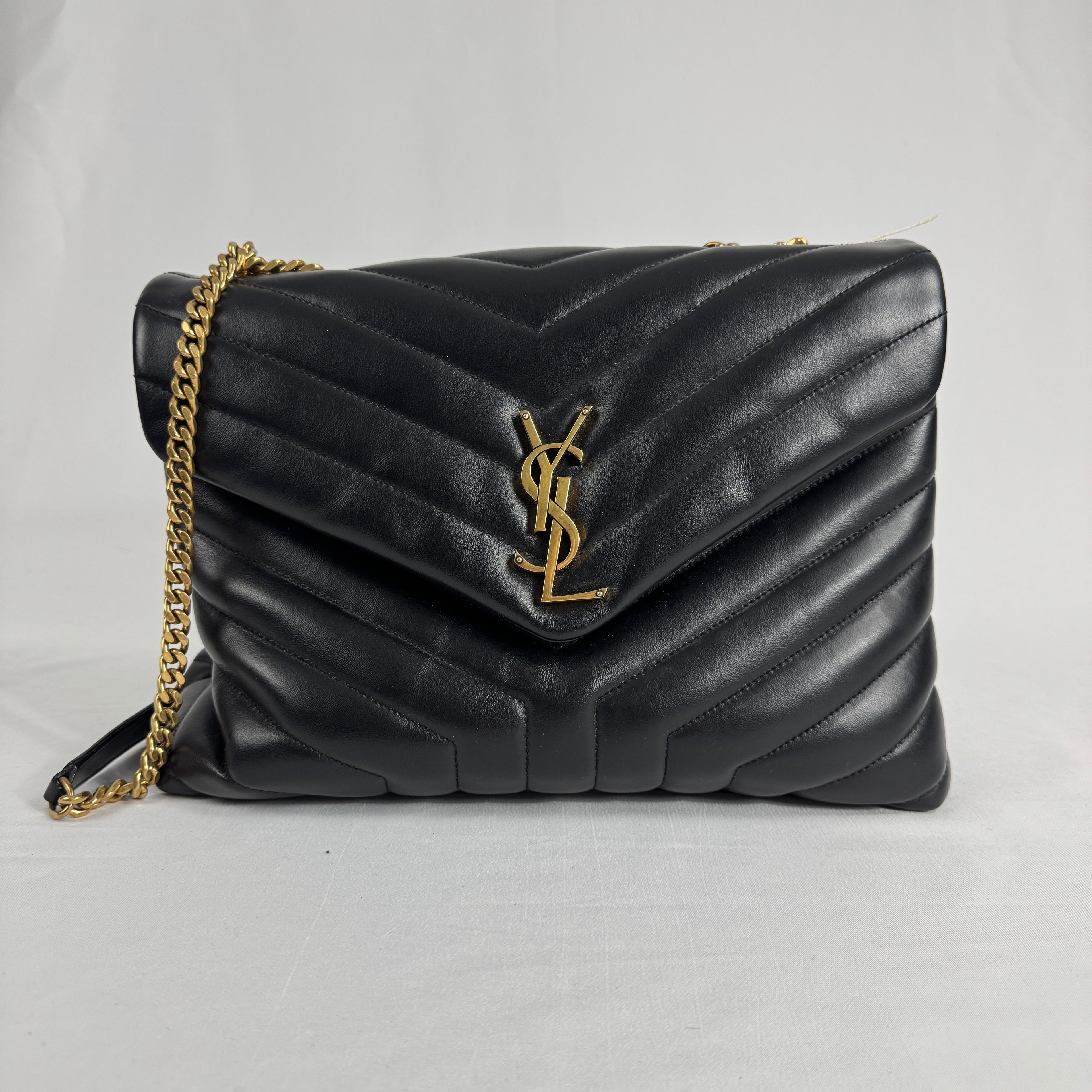 The Saint Laurent LouLou Crossbody Bag is a quilted leather handbag featuring the signature YSL logo, a chain strap, and a