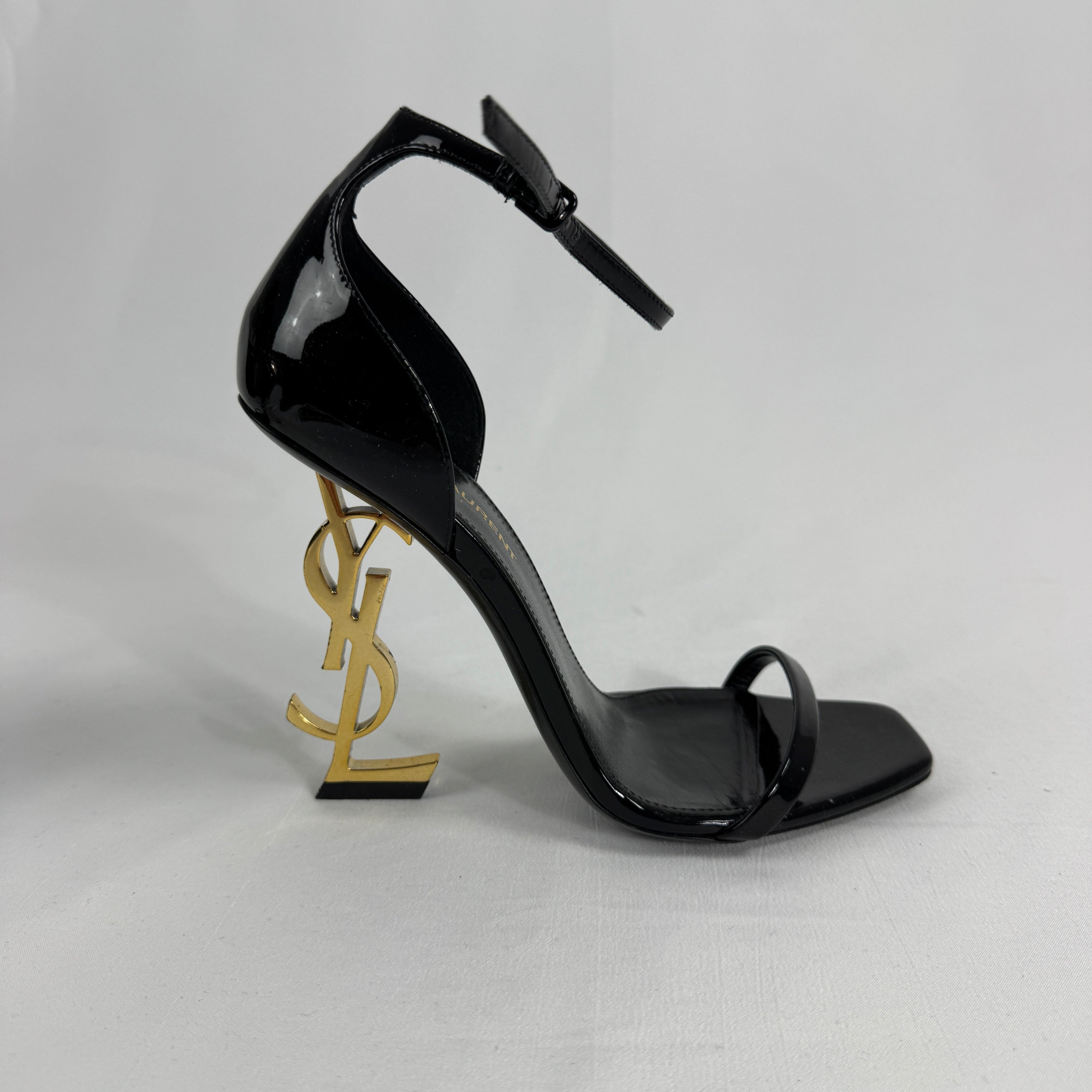 The Saint Laurent Opyum 110 is an iconic high-heel sandal renowned for its striking YSL logo heel. Crafted from premium
