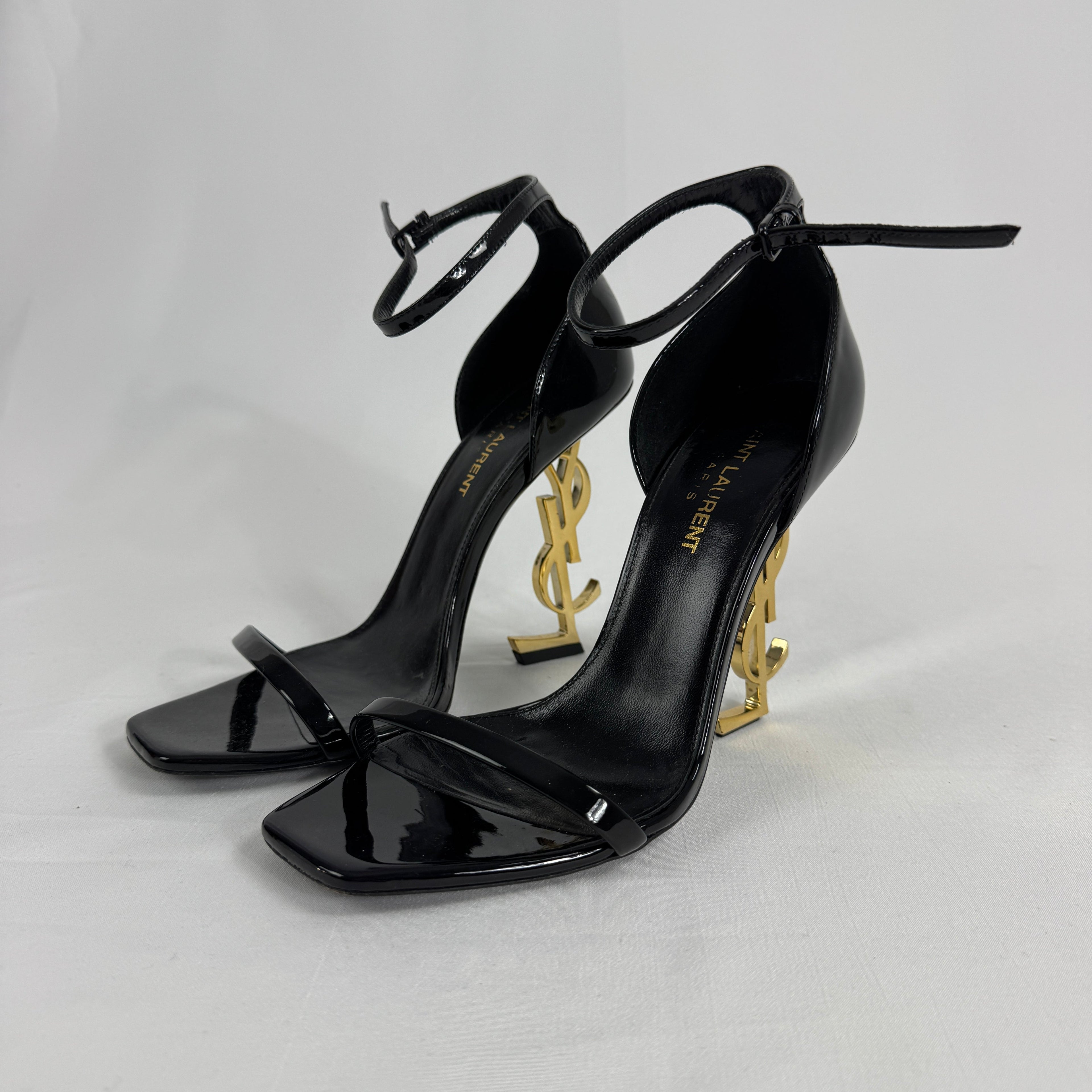 The Saint Laurent Opyum 110 is an iconic high-heel sandal renowned for its striking YSL logo heel. Crafted from premium