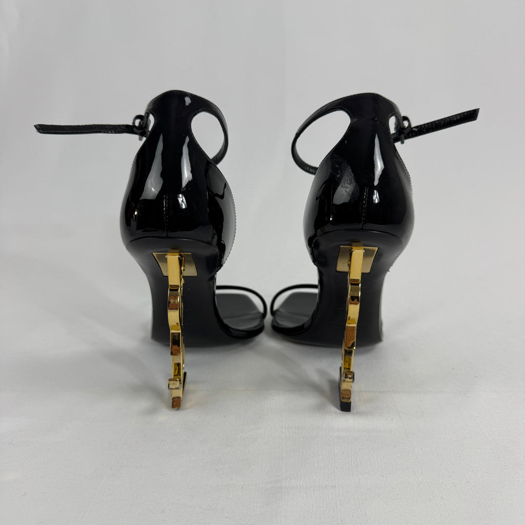 The Saint Laurent Opyum 110 is an iconic high-heel sandal renowned for its striking YSL logo heel. Crafted from premium