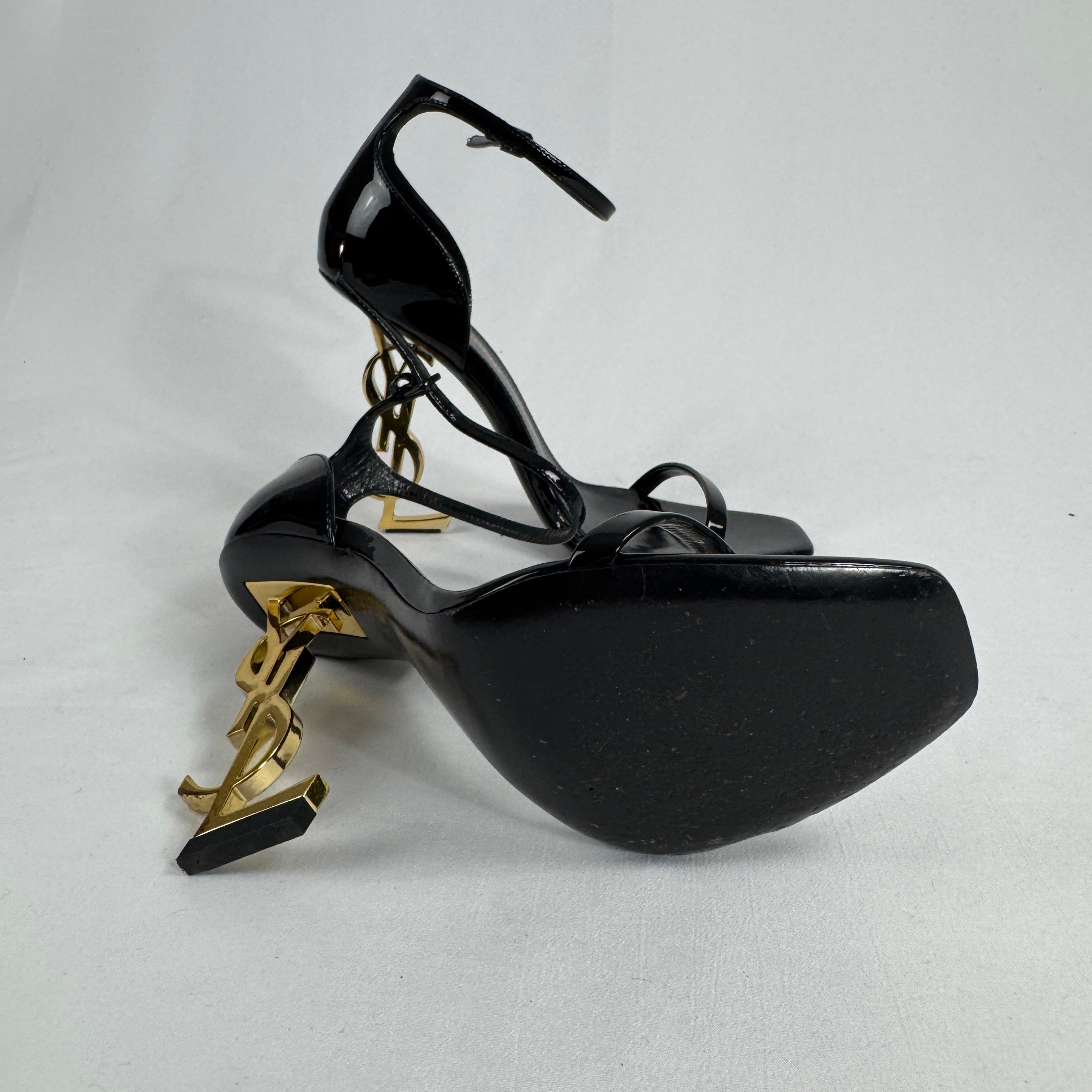 The Saint Laurent Opyum 110 is an iconic high-heel sandal renowned for its striking YSL logo heel. Crafted from premium
