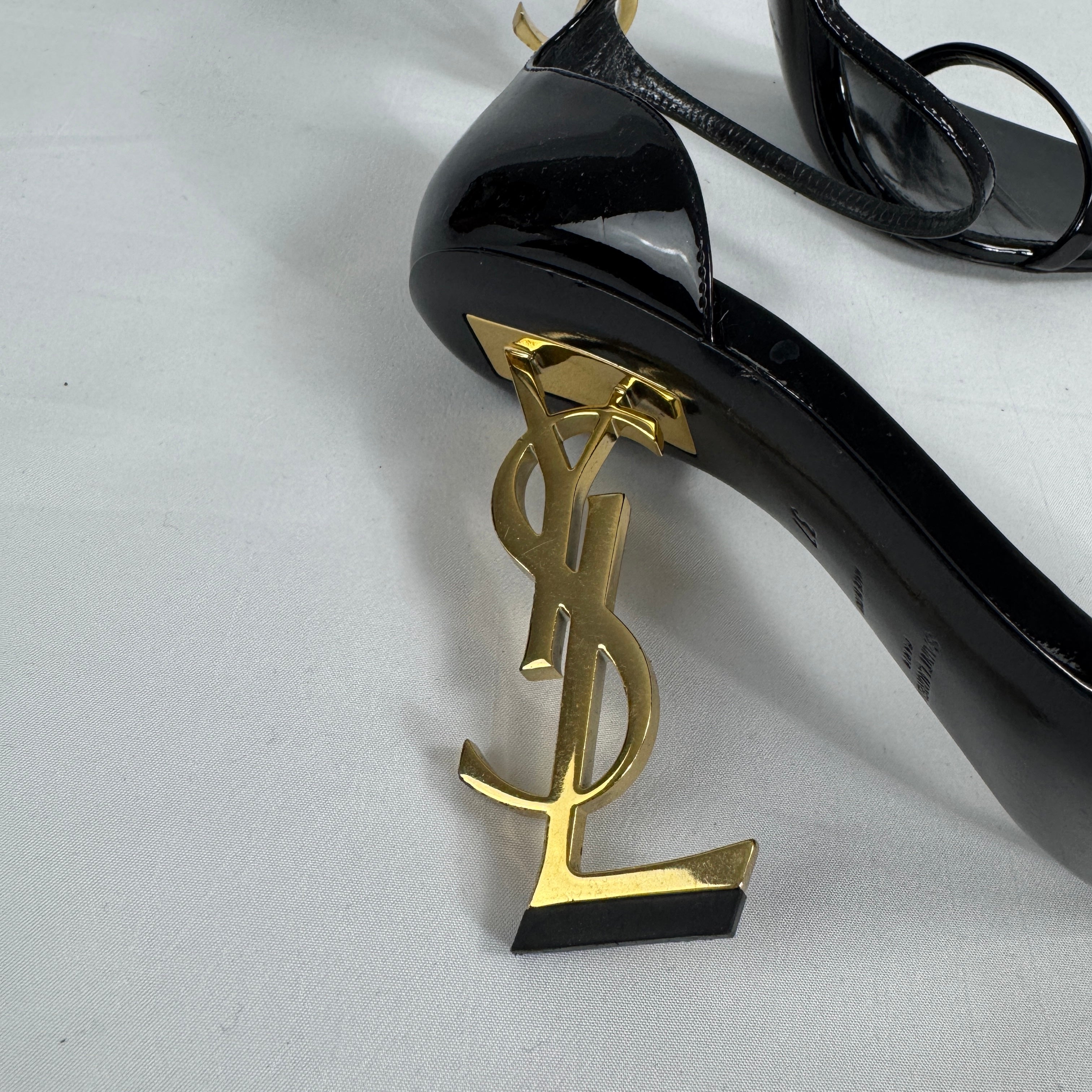 The Saint Laurent Opyum 110 is an iconic high-heel sandal renowned for its striking YSL logo heel. Crafted from premium