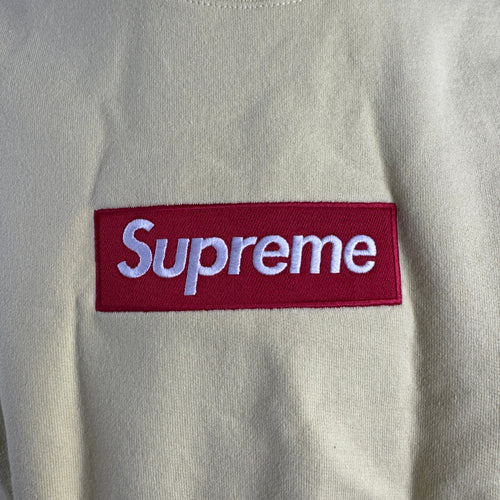The Supreme Box Logo in pale yellow refers to a signature Supreme piece featuring the iconic box logo graphic set against a