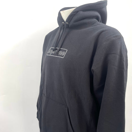 The Supreme KAWS Chalk Hooded Sweatshirt Black is a heavyweight cotton hoodie featuring KAWS’ signature chalk-style Box Logo