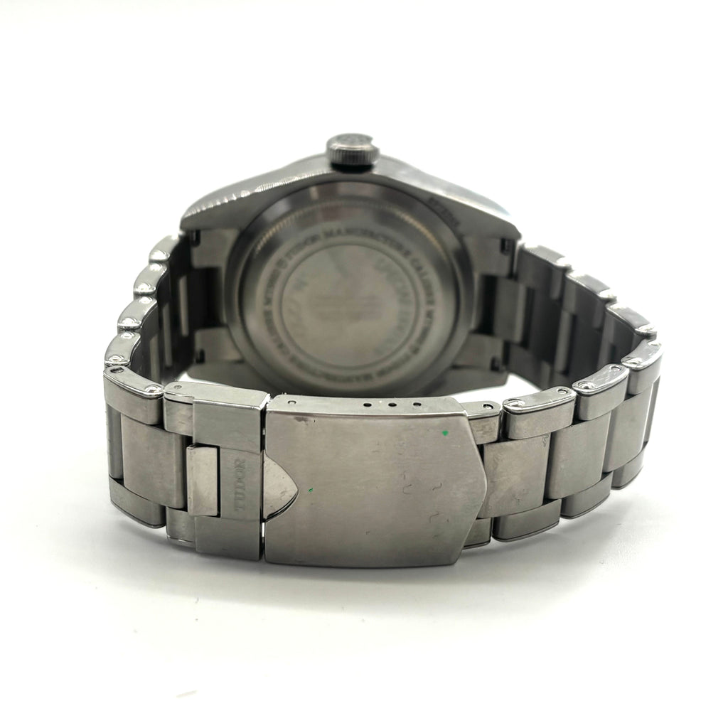 Close-up of a Tudor Black Bay Harrods watch showing the stainless steel clasp and engraved case back against a white background.
