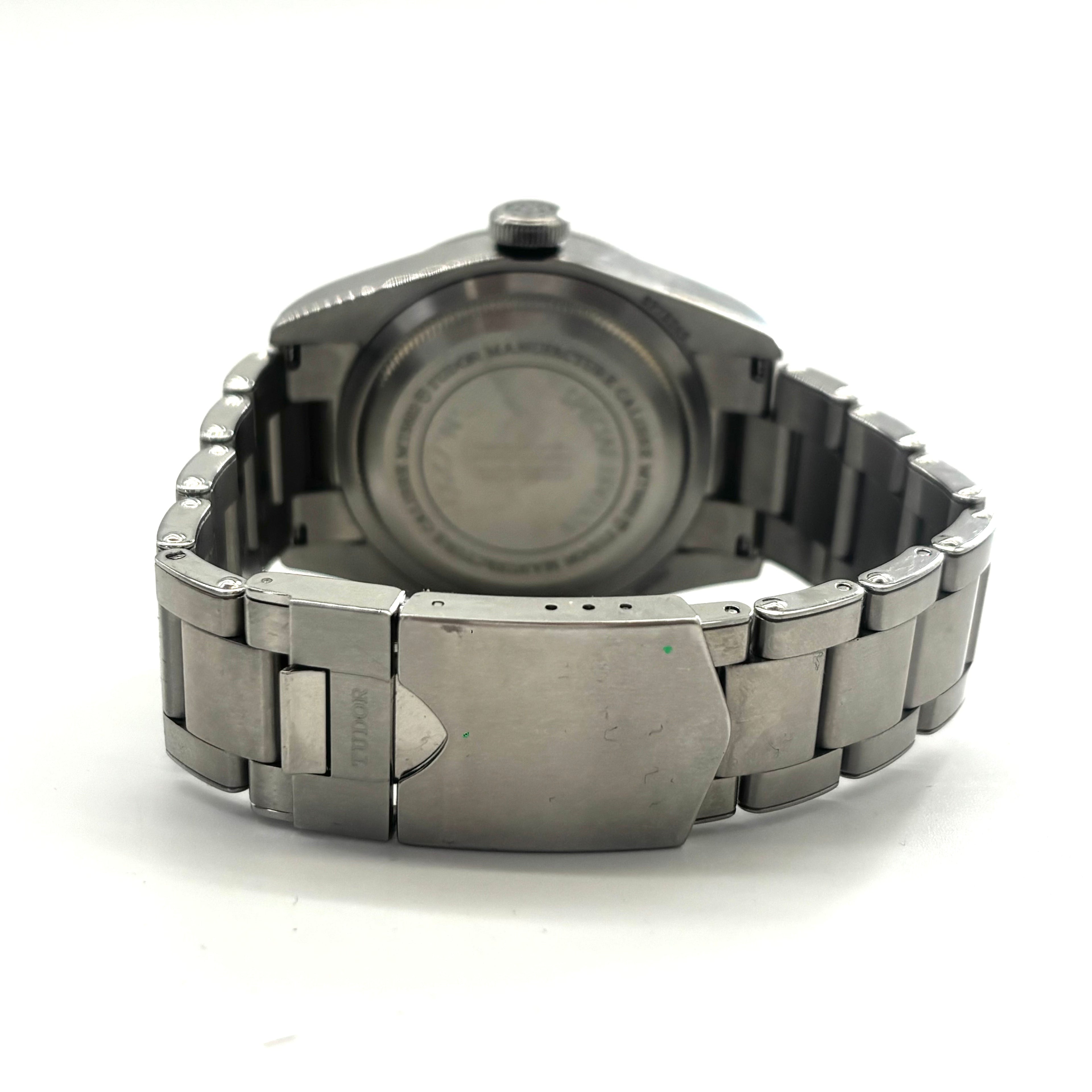 Close-up of a Tudor Black Bay Harrods watch showing the stainless steel clasp and engraved case back against a white background.