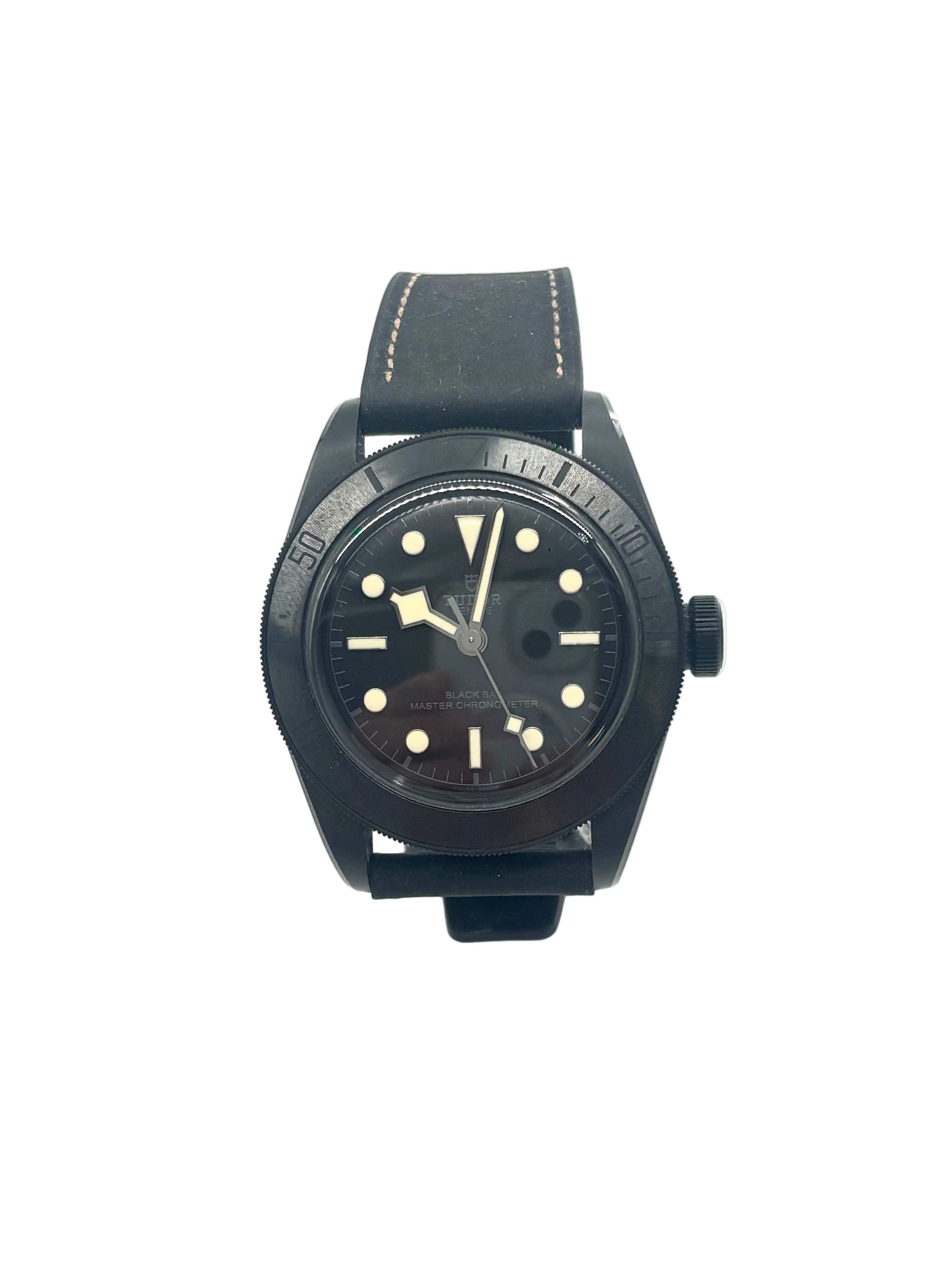 TUDOR black ceramic wristwatch with round face, bold markers, thick hands, black stitched leather strap and rotating bezel on white background.